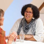 Zwei Personen im Gespräch an einem Stehtisch an der Präsident*innenkonferenz von Agile. Die Szene wirkt wie ein informelles Gespräch bei einer Veranstaltung oder einem Netzwerktreffen.